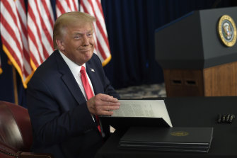 President Donald Trump smiles as he is about to sign four executive orders during a news conference at the Trump National Golf Club in New Jersey on August 8.