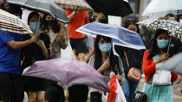 Protected but not over-protected: masked people in the rain in Singapore.