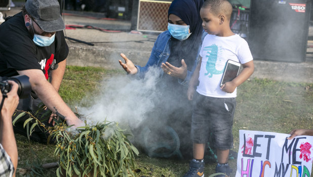 Sabah Siyad and her son Saami participates in a smoking ceremony at the rally.