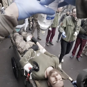 Taira assists as a serviceman is brought in on a stretcher in Mariupol.