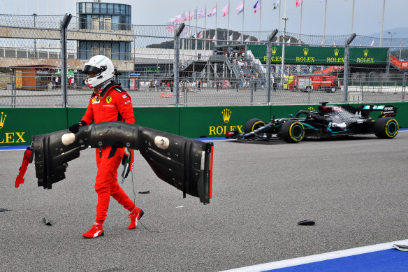 Sebastian Vettel retrieves his front wing as Hamilton drives past.