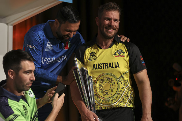 Australian captain Aaron Finch, right, holds the trophy at a media event ahead of the men’s T20 World Cup. 