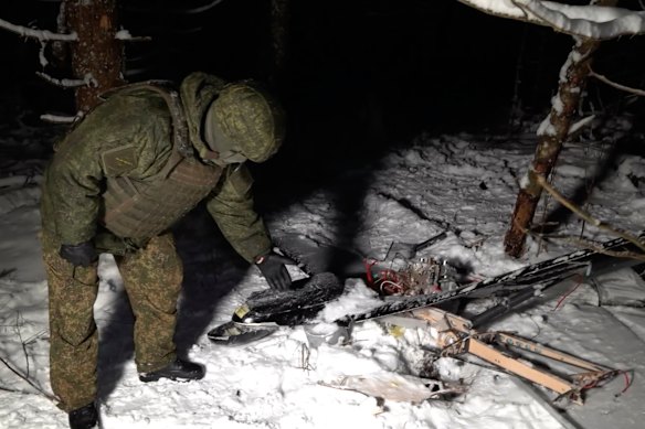 This image made from undated video provided by the Russian Defence Ministry Press Service shows a man standing by what it said was a downed drone involved in an alleged attack on a residence of President Vladimir Putin.