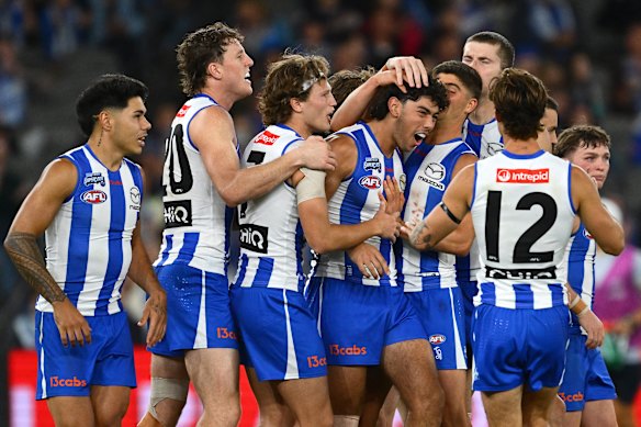 Cooper Trembath of the Kangaroos is congratulated by team mates after kicking a goal.