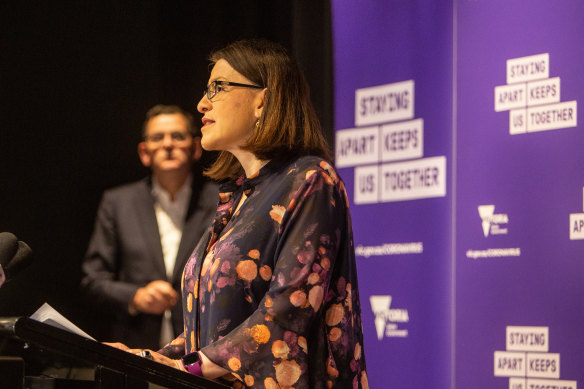 Daniel Andrews watches his then health minister Jenny Mikakos at the podium.