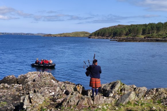 A piper gives Ponant guests a welcome and a send-off at Loch Ewe.