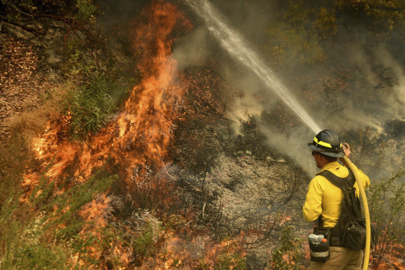 A firefighter puts out a hotspot north-west of Forrest Falls in California as the El Dorado Fire continues to burn.