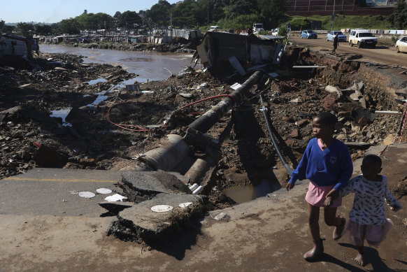 Children walk on damaged road at an informal settlement in Durban.