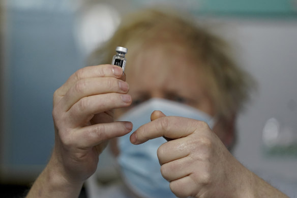 Britain’s Prime Minister Boris Johnson holds a bottle of the Pfizer vaccine as he visits a COVID-19 vaccination centre.