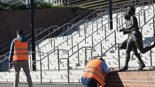 Workers remove the coverings of the plaques on Tuesday afternoon. 