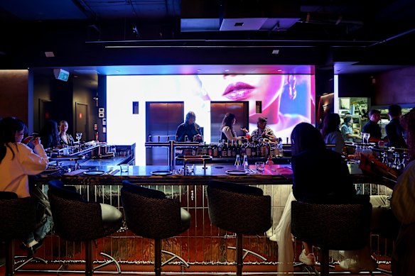 Projections of beautiful people behind the bar.