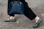 A guest wears white jacket, black skirt, Alaia shoes, navy bag outside Ferragamo during the Milan Fashion Week Menswear Spring/Summer 2025 on September 21, 2024 in Milan, Italy.