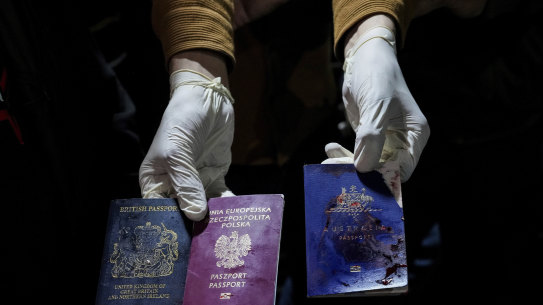 A man displays blood-stained British, Polish, and Australian passports