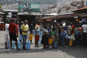 People wait in line to stockpile drinking water in Port-au-Prince ahead of further protests.