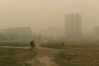 A man rides his bicycle through smoke from a fire in Yakutsk in Russia’s far east as a heat wave swept across Siberia.