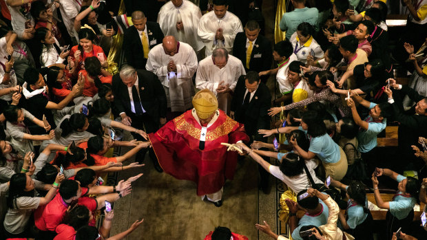 Francis walks out from Assumption Cathedral as Thai youth reach out to touch him in Bangkok on Friday.