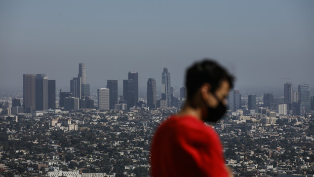 A man wears a face mask while visiting the Griffith Observatory overlooking downtown Los Angeles.