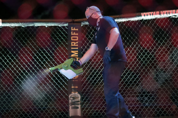 A worker sprays sanitiser in the octagon between bouts at UFC 249.
