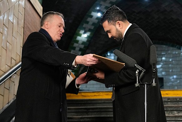New York Mayor Zohran Mamdani signs a registry as city clerk Michael McSweeney holds the book after Mamdani was sworn in as mayor.
