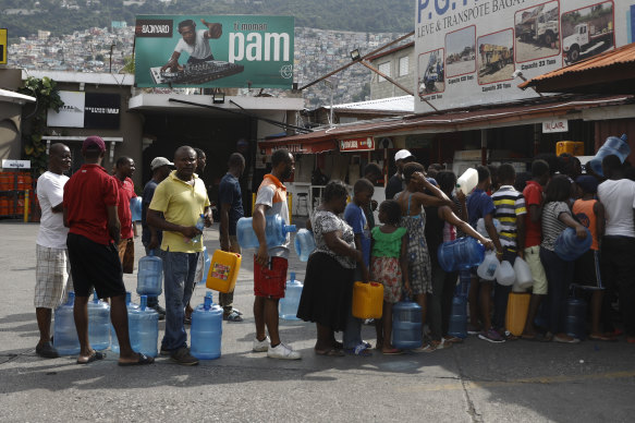 People wait in line to stockpile drinking water in Port-au-Prince ahead of further protests.