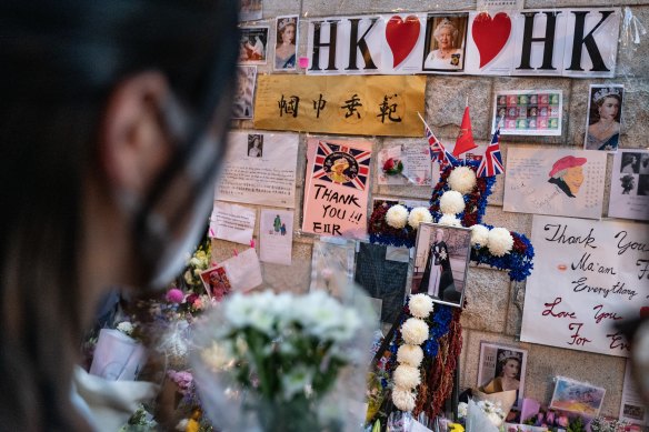 A woman lays flowers as a tribute to Queen Elizabeth II outside the British Consulate in Hong Kong.