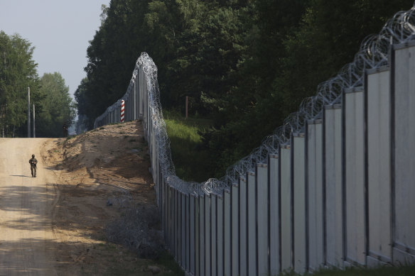 A Polish border guard patrols a metal wall on the border between Poland and Belarus, near Kuznice, Poland.