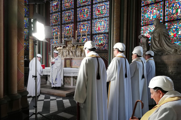 The Archbishop of Paris Michel Aupetit, second left, leads the first mass in a side chapel, two months after a devastating fire engulfed the Notre-Dame de Paris cathedral.