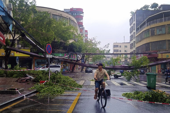 A cyclist rides past fallen debris and trees in the aftermath of heavy storms in Qingyuan, Guangdong province.