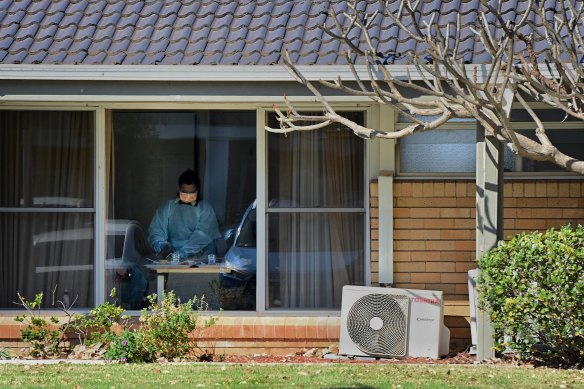 A healthcare worker in PPE inside an aged care facility.