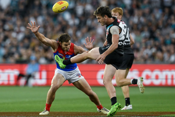 Zak Butters of the Power kicks over Jack Viney of the Demons.
