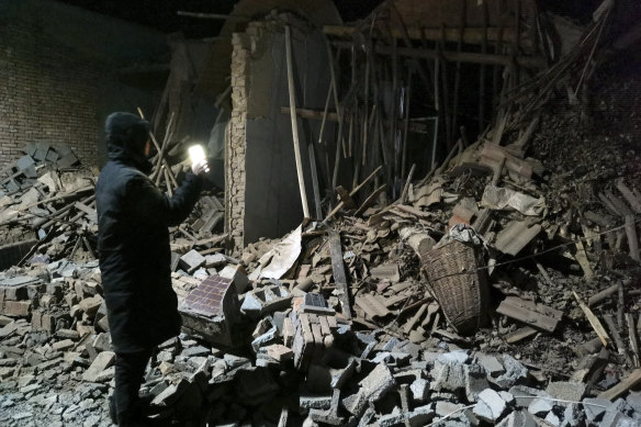 A government worker looks at the debris of a house brought down in the earthquake in Jishishan county in northwest China’s Gansu province .