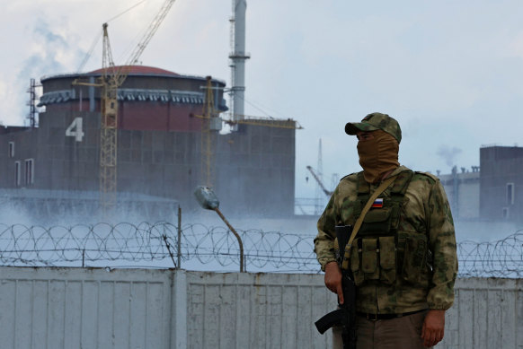 A serviceman with a Russian flag on his uniform stands guard near the Ukrainian Zaporizhzhia Nuclear Power Plant now controlled by Moscow.