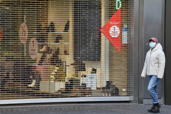 A man walks past a closed shop in Cologne on the day a harder lockdown came into force across Germany.