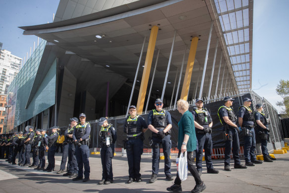 A woman walks past a police barricade outside the Melbourne Convention and Exhibition Centre on Tuesday. Thousands of protesters are expected outside on Wednesday.