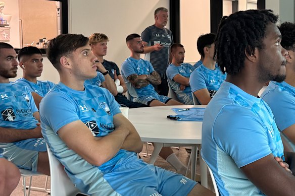 Sydney FC coach Ufuk Talay delivers a team meeting wearing the Timekettle device, while Peruvian import Piero Quispe (second from left) listens to the Spanish translation.