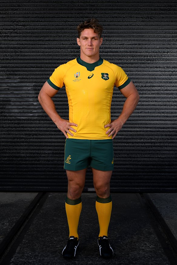 The away strip is predominantly green, with an Indigenous design in gold relief.