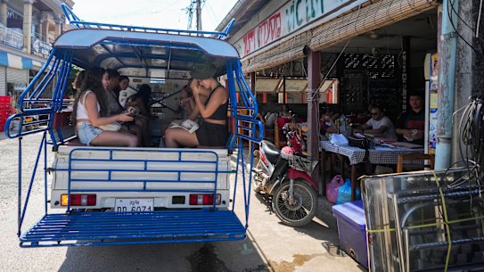 Foreign tourists leave on a vehicle after having food and beer in a bar with restaurant in Vang Vieng.