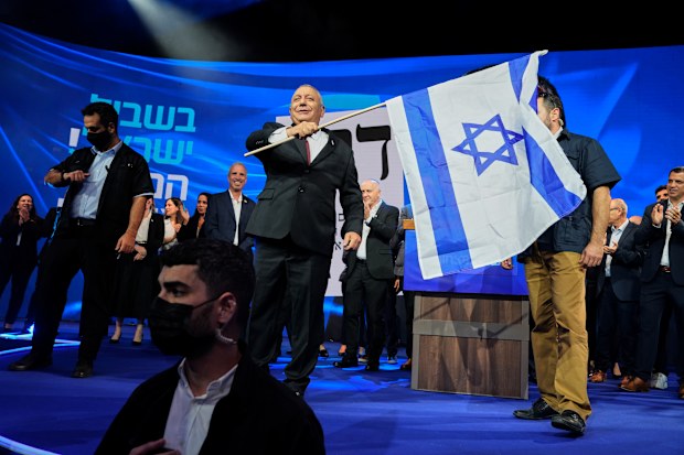 Gadi Eisenkot, leader of the Yashar (“Straight”) party, waves an Israeli flag onstage following the release of the first exit poll results.