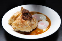 Roti banjir - roti bread in curry sauce with two soft-boiled eggs and sambal.