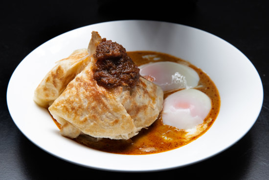 Roti banjir - roti bread in curry sauce with two soft-boiled eggs and sambal.