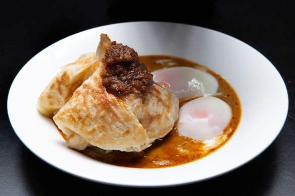 Roti banjir - roti bread in curry sauce with two soft-boiled eggs and sambal.