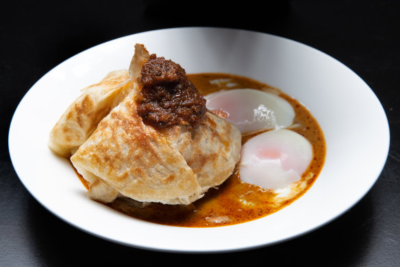 Roti banjir - roti bread in curry sauce with two soft-boiled eggs and sambal.