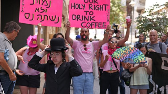 Un giovane manifestante ultra-ortodosso resta fermo fuori dal Café Basimta mentre i contro-manifestanti esprimono il loro punto di vista. Ora il bar è stato costretto a chiudere.