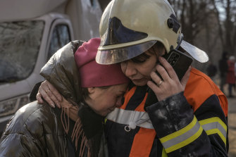 Salı günü Ukrayna'nın Kiev kentinde bir yerleşim bölgesinde meydana gelen bombalı saldırının ardından bir itfaiyeci yıkılan bir apartmanın dışında bir kadını teselli ediyor.