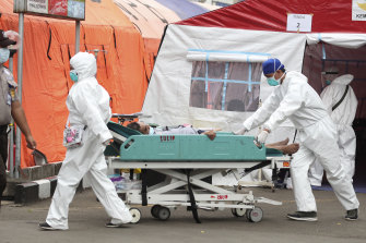 Paramedics roll a man on a hospital bed past emergency tents erected to accommodate a surge of COVID-19 patients at a hospital in Bekasi, on the outskirts of Jakarta.