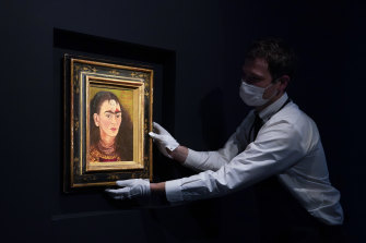 An art handler adjust Frida Kahlo’s “Diego y yo” on display at Sotheby’s auction house.