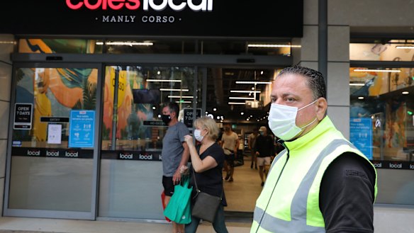 Masked shoppers and a COVID marshal outside Coles in Manly.