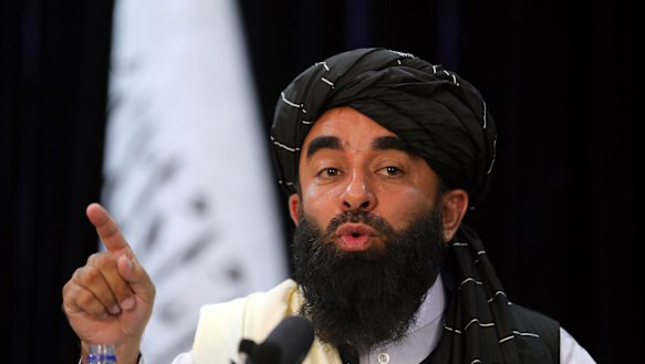 In front of a Taliban flag, Taliban spokesman Zabihullah Mujahid speaks at at his first news conference, in Kabul, on Tuesday. The group’s websites were offline on Saturday.