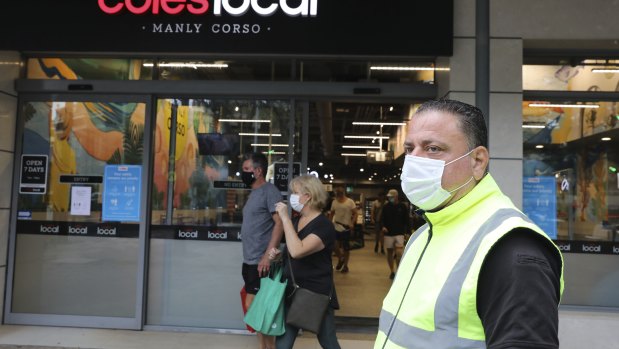 Masked shoppers and a COVID marshal outside Coles in Manly.