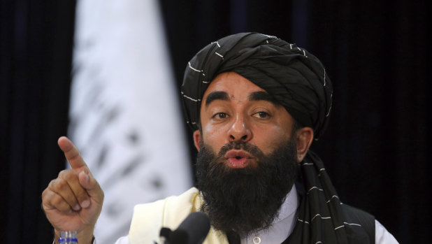 In front of a Taliban flag, Taliban spokesman Zabihullah Mujahid speaks at at his first news conference, in Kabul, on Tuesday. The group’s websites were offline on Saturday.
